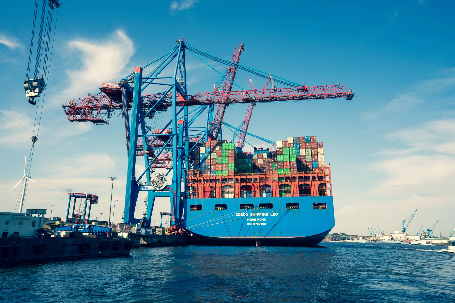 Container ship being handled by cranes at a busy cargo terminal