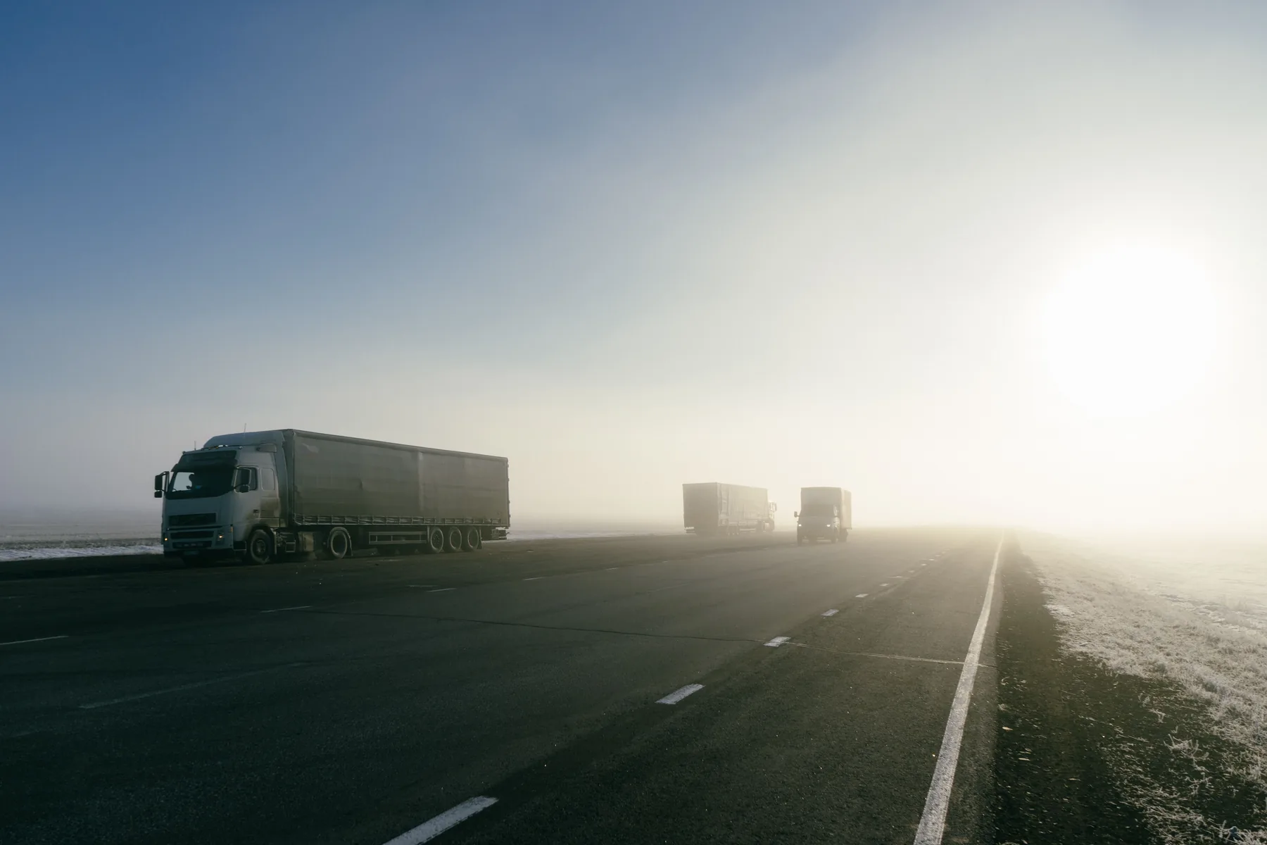 Freight trucks travelling on a highway in early morning light