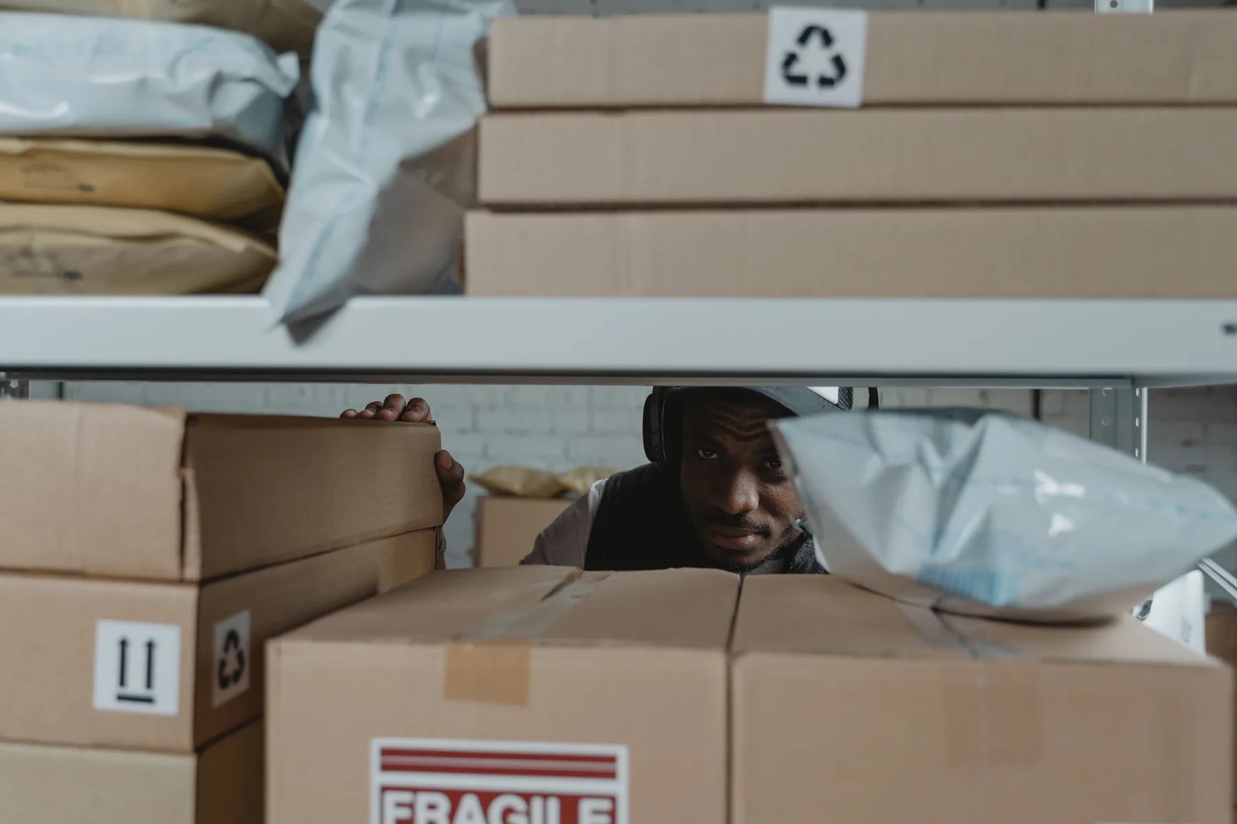 Logistics worker inspecting parcels on warehouse shelves