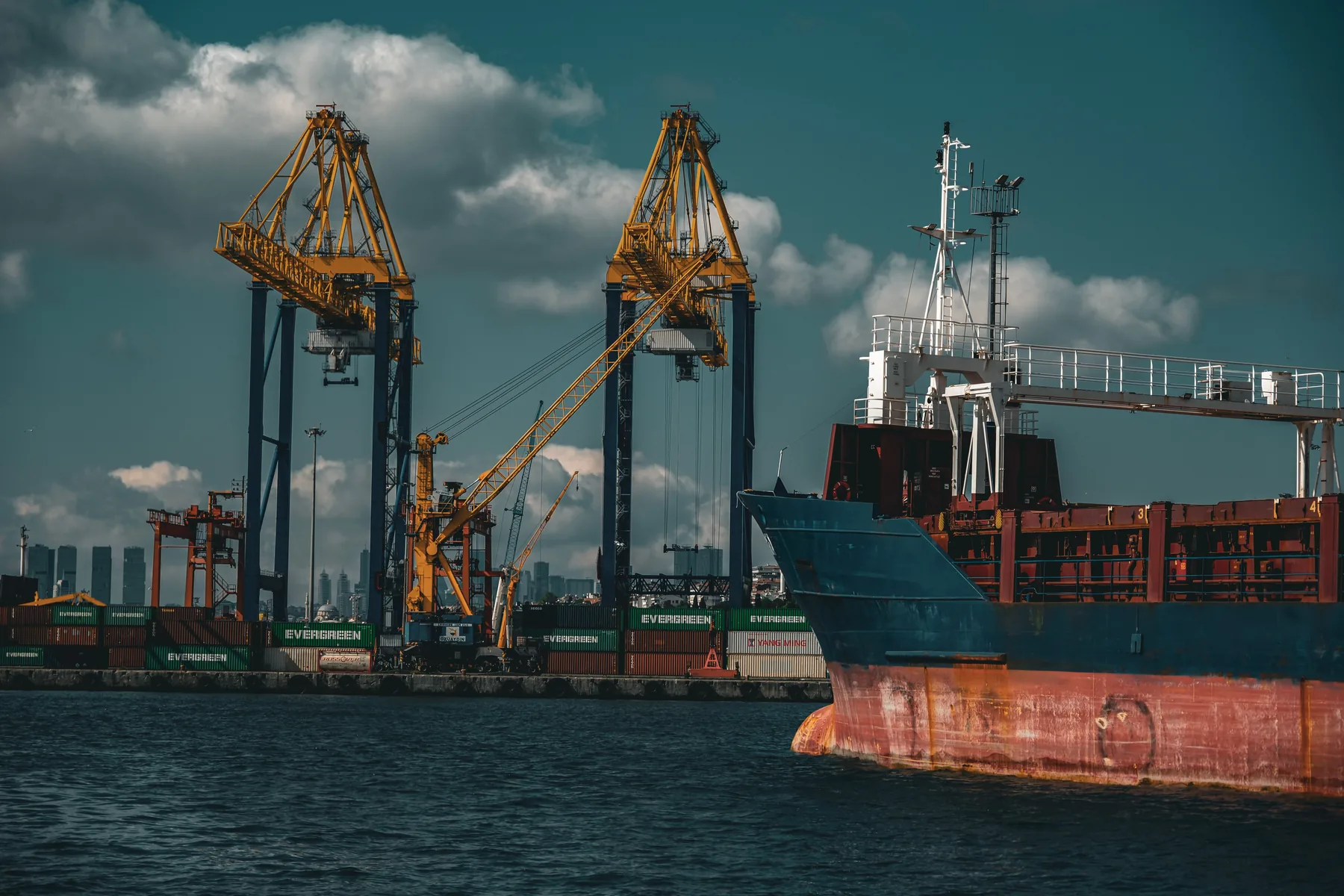 Cargo vessel positioned beside port cranes and containers